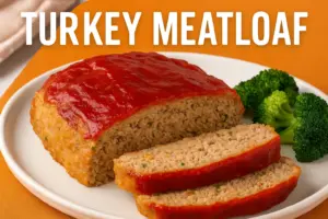 Juicy homemade turkey meatloaf with tomato glaze served with steamed broccoli on a white plate.